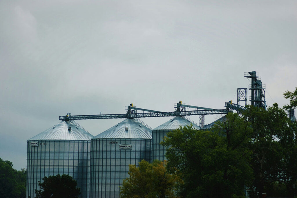 Three silos next to some trees.