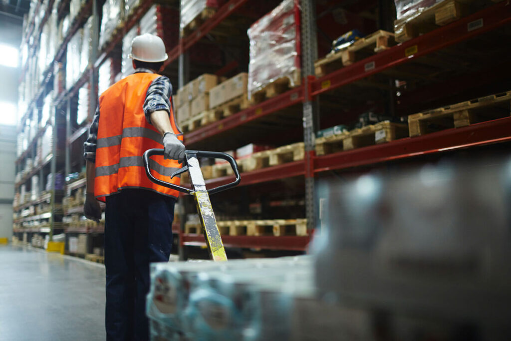 Man pulling a forklift full of products.