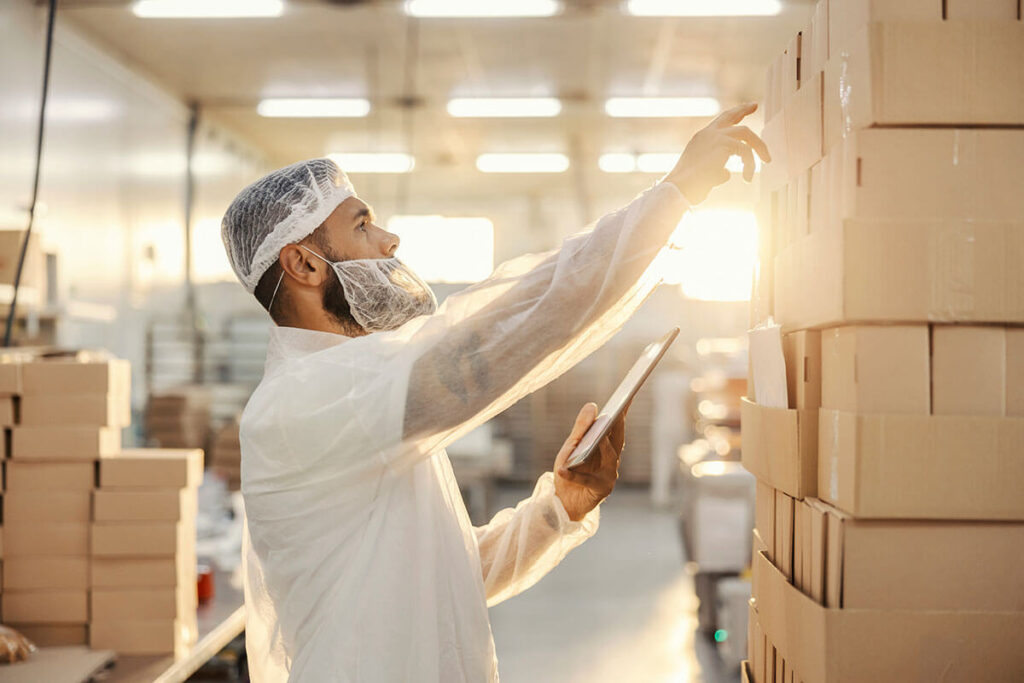 Man pointing at boxes with a clipboard in the other hand.