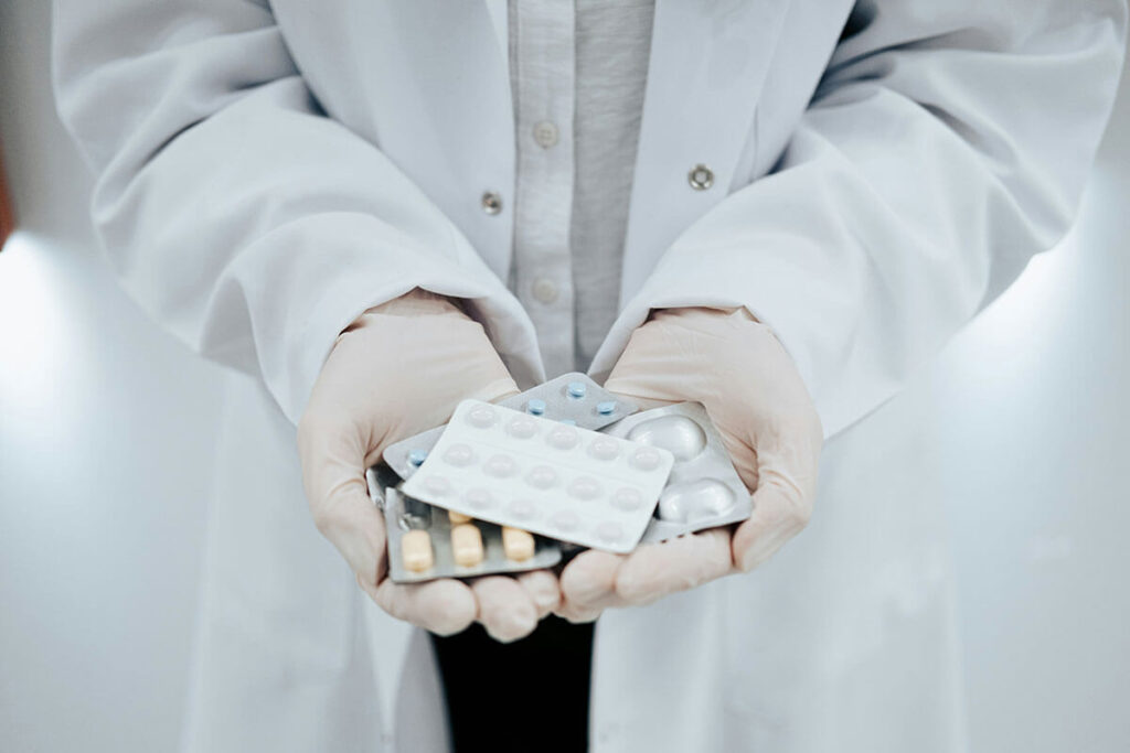 Someone holding a hand full of different types of pills.